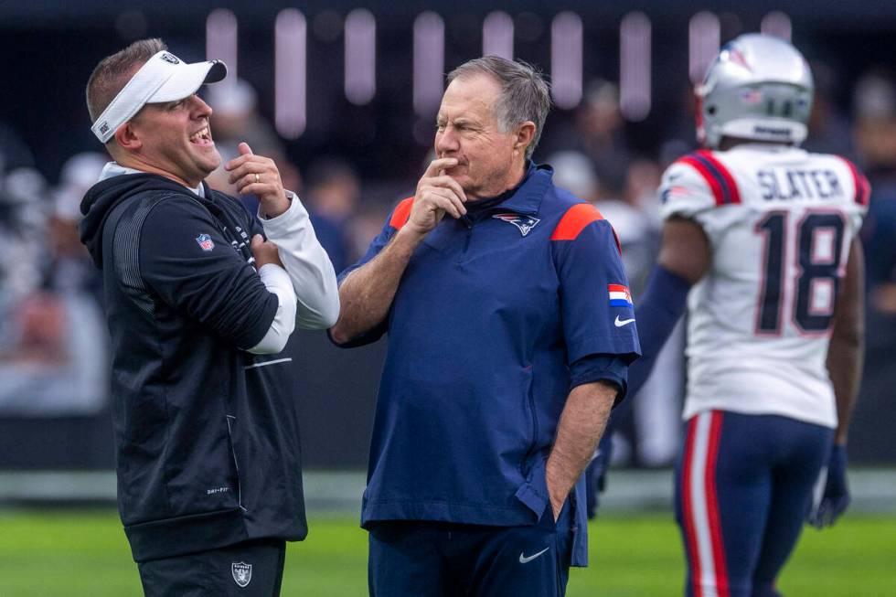 Raiders Head Coach Josh McDaniels talks with New England Patriots Head Coach Bill Belichick dur ...