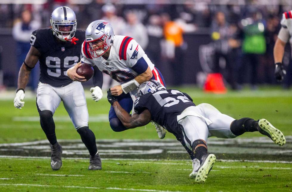 New England Patriots quarterback Mac Jones (10) is stopped by a diving Raiders linebacker Denze ...