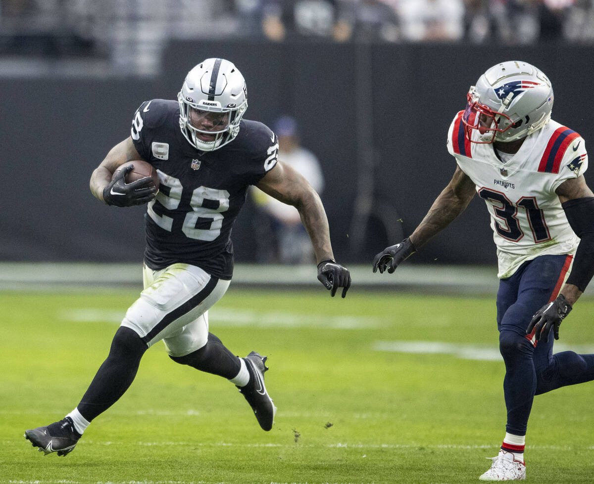 Raiders running back Josh Jacobs (28) rushes against New England Patriots cornerback Jonathan J ...