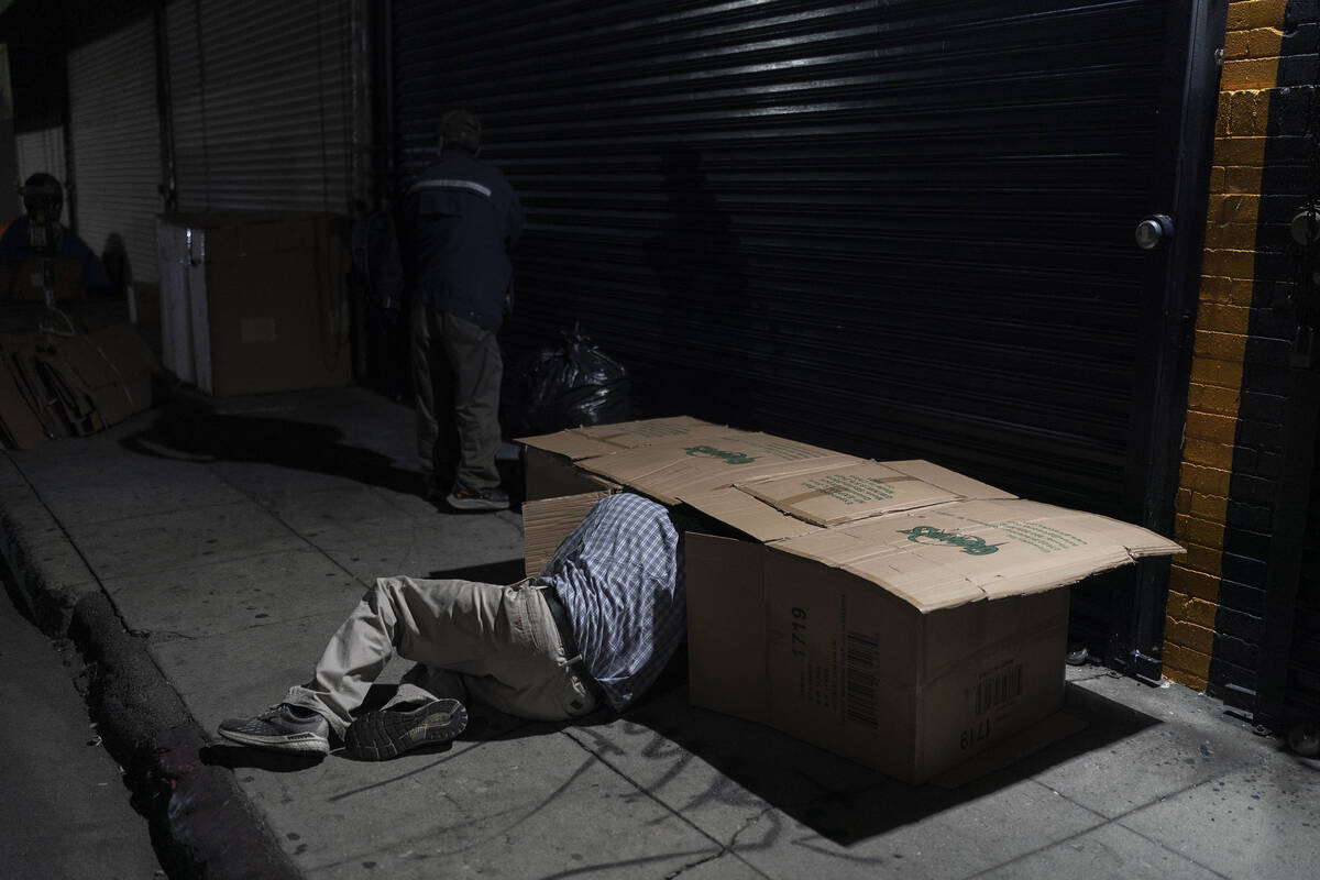 FILE - David Hernandez, a 62-year-old homeless man, crawls into his bed made with cardboard box ...