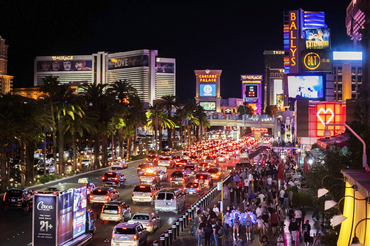 FILE - Vehicles and crowds move along the strip in Las Vegas on March 19, 2021. Caesars Enterta ...