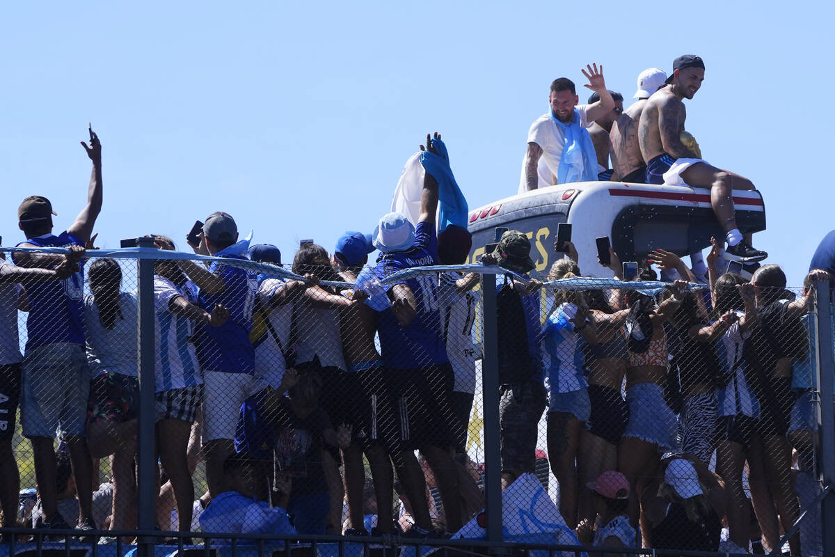 Lionel Messi waves from the rooftop of an open top bus transporting the national soccer team th ...