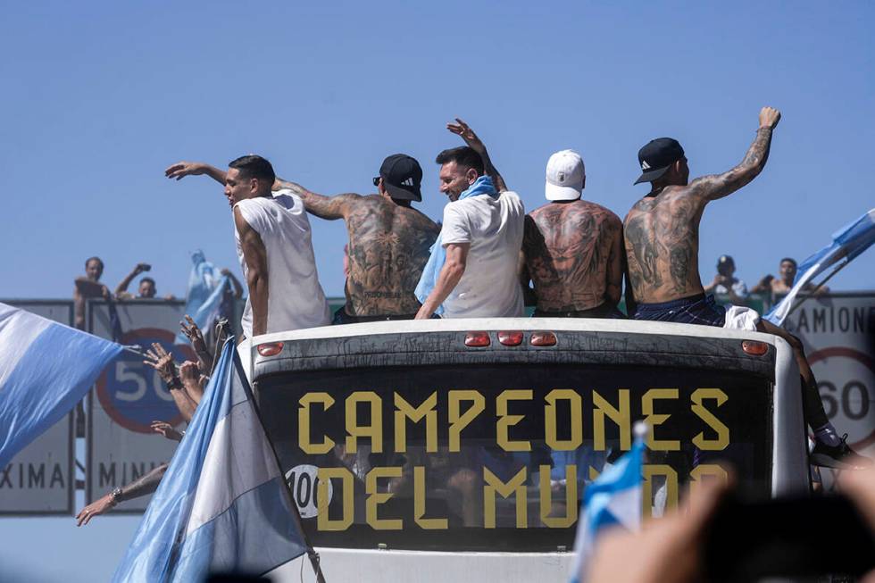 Lionel Messi, center and teammates wave from an open top bus driving the soccer team that won t ...