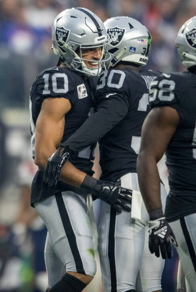 Raiders wide receiver Mack Hollins (10) celebrates with safety Duron Harmon (30) after downing ...