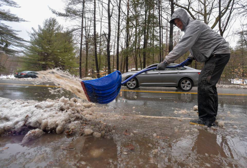 Dean Stahman, a Brattleboro, Vt., resident, clears off some slush and water from his driveway a ...