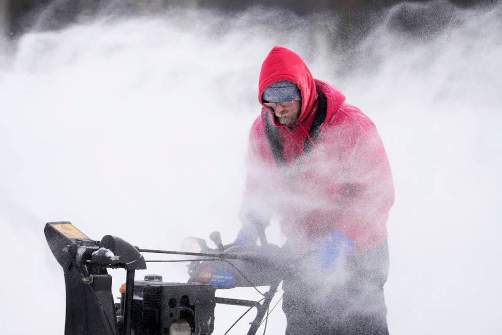 Mark Sorter clears snow from a downtown ice skating rink, Friday, Dec. 23, 2022, in Des Moines, ...