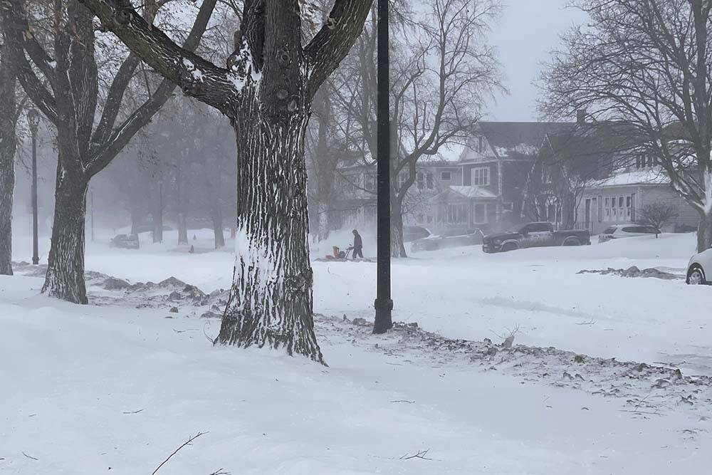 A person clears snow from the sidewalk during a snowstorm on Saturday, Dec. 24, 2022 in Buffalo ...