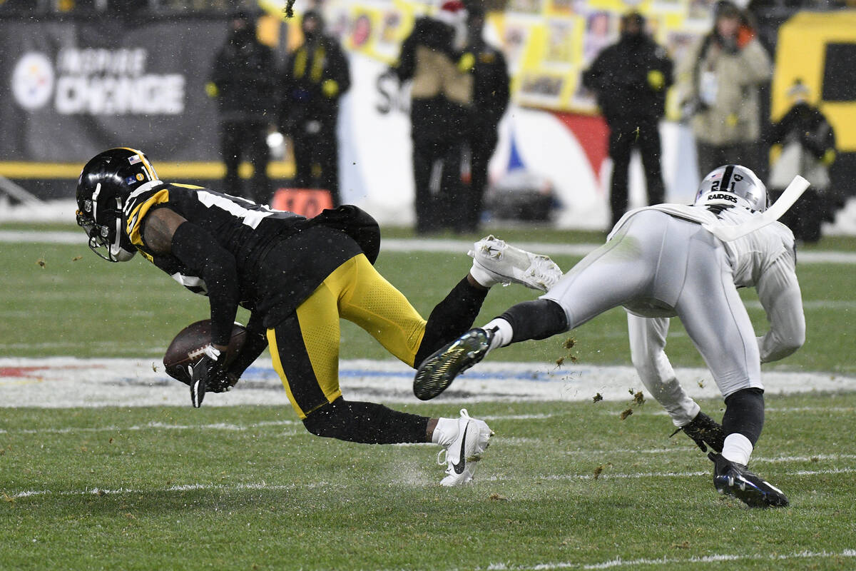 Pittsburgh Steelers wide receiver Diontae Johnson, left, is brought down by Las Vegas Raiders c ...