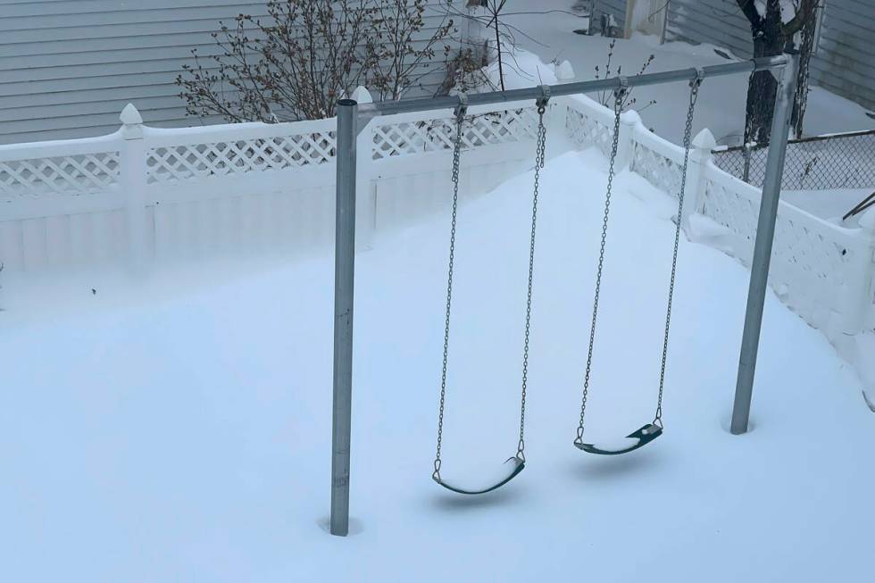 A snow drift nearly touches the bottom of two swings, Sunday, Dec. 25, 2022, in a neighborhood ...