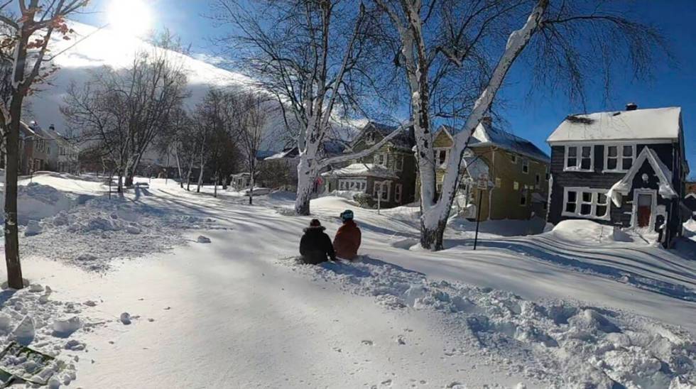 This photo provided by Clare Purcell shows two people sitting outside on their front lawn after ...