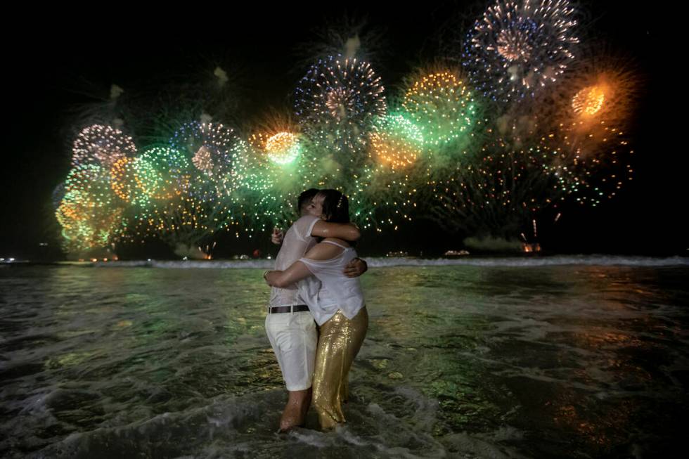 People celebrate the start of the New Year, backdropped by fireworks exploding in the backgroun ...