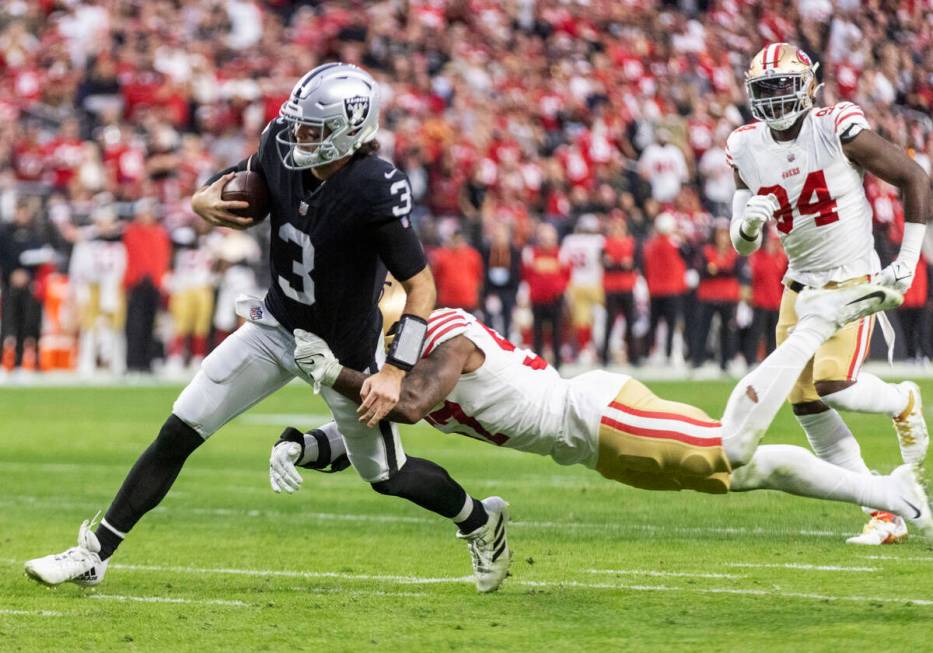 Raiders quarterback Jarrett Stidham (3) tries to shake a tackle from San Francisco 49ers lineba ...