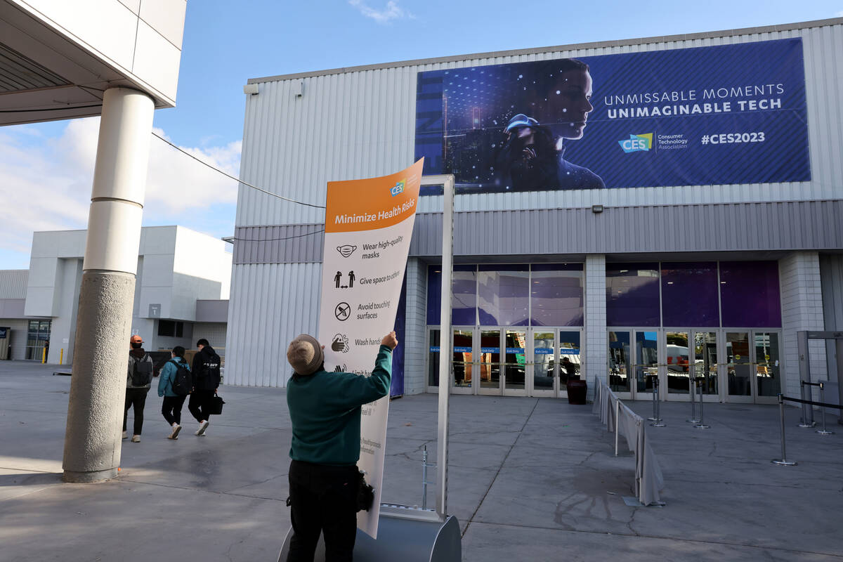 A worker places a sign ahead of CES at the Las Vegas Convention Center Tuesday, Jan. 3, 2023. T ...