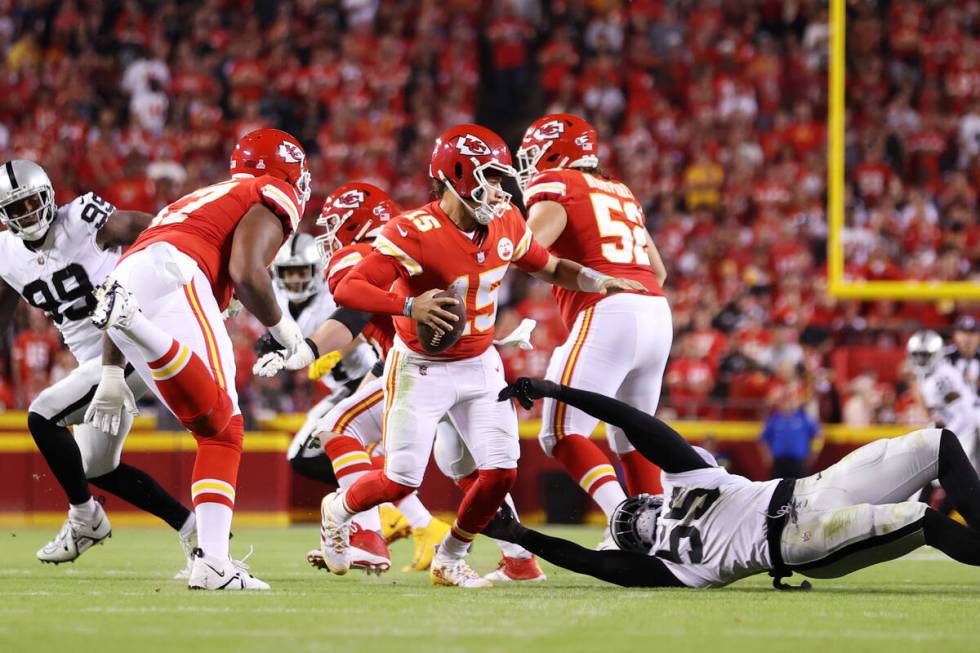 Kansas City Chiefs quarterback Patrick Mahomes (15) avoids a tackle from Raiders defensive end ...