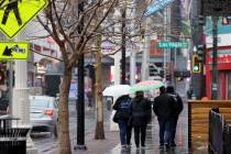 People walk in the rain on Fremont Street near Las Vegas Boulevard in Las Vegas Tuesday, Jan. 1 ...