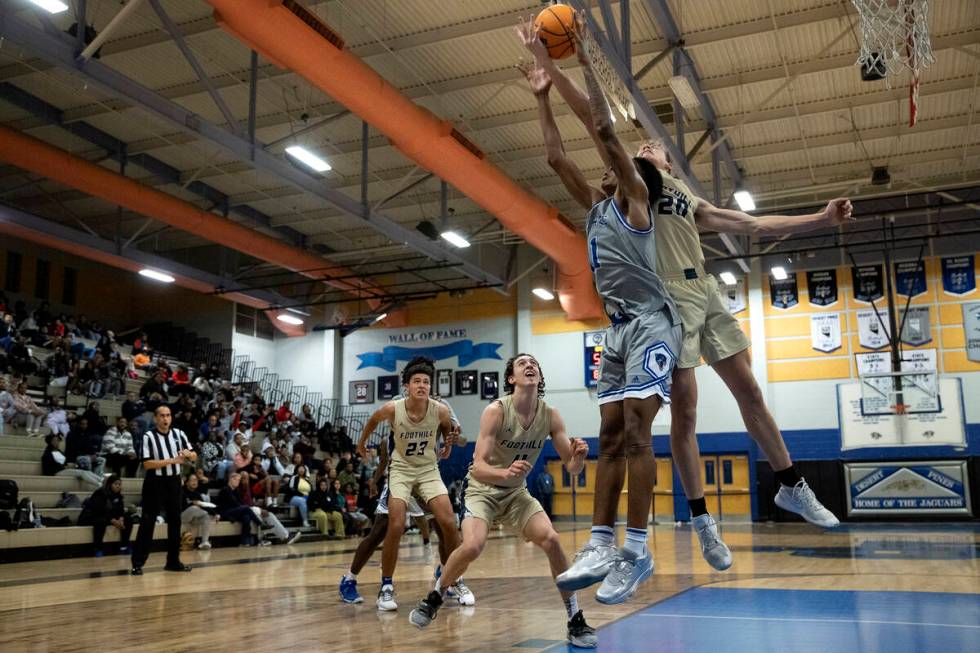 Desert Pines’ Evan Tatum (11) and Brock Stearman (20) jump for a rebound during a boys h ...