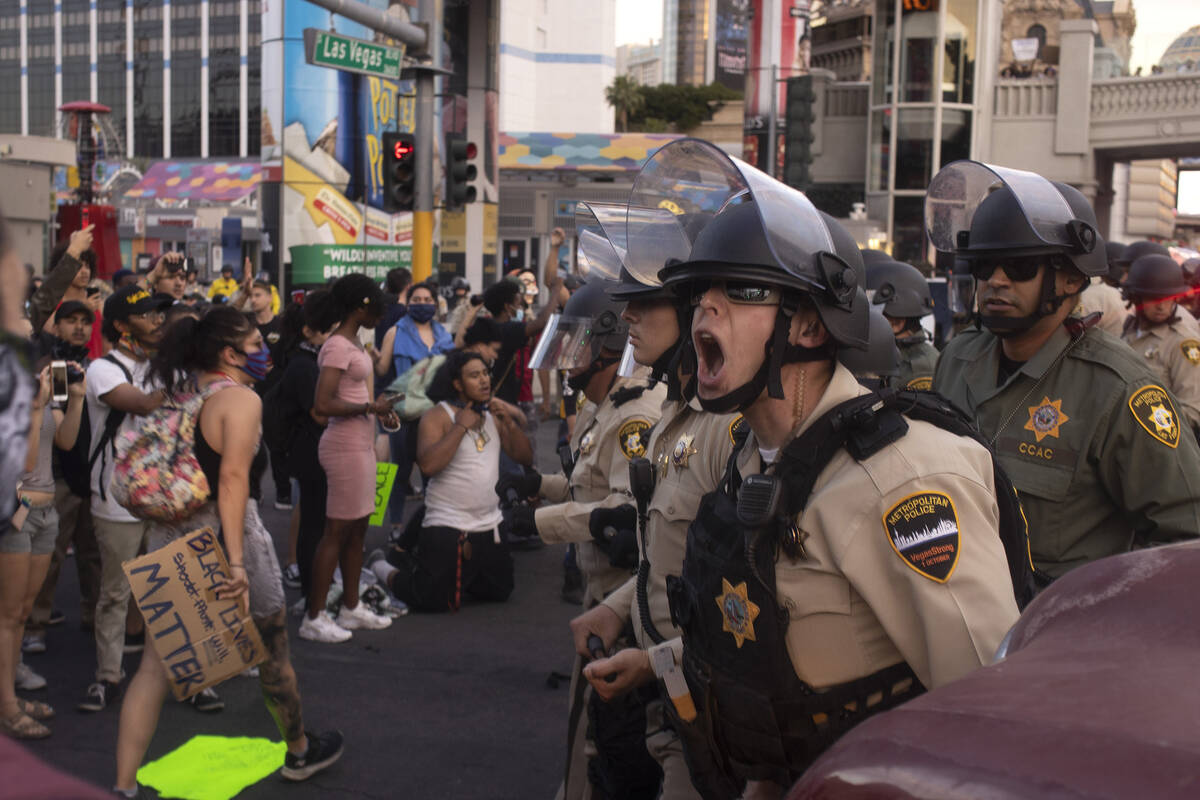 A Metropolitan police officer screams at protesters to back up as the protest, calling for raci ...