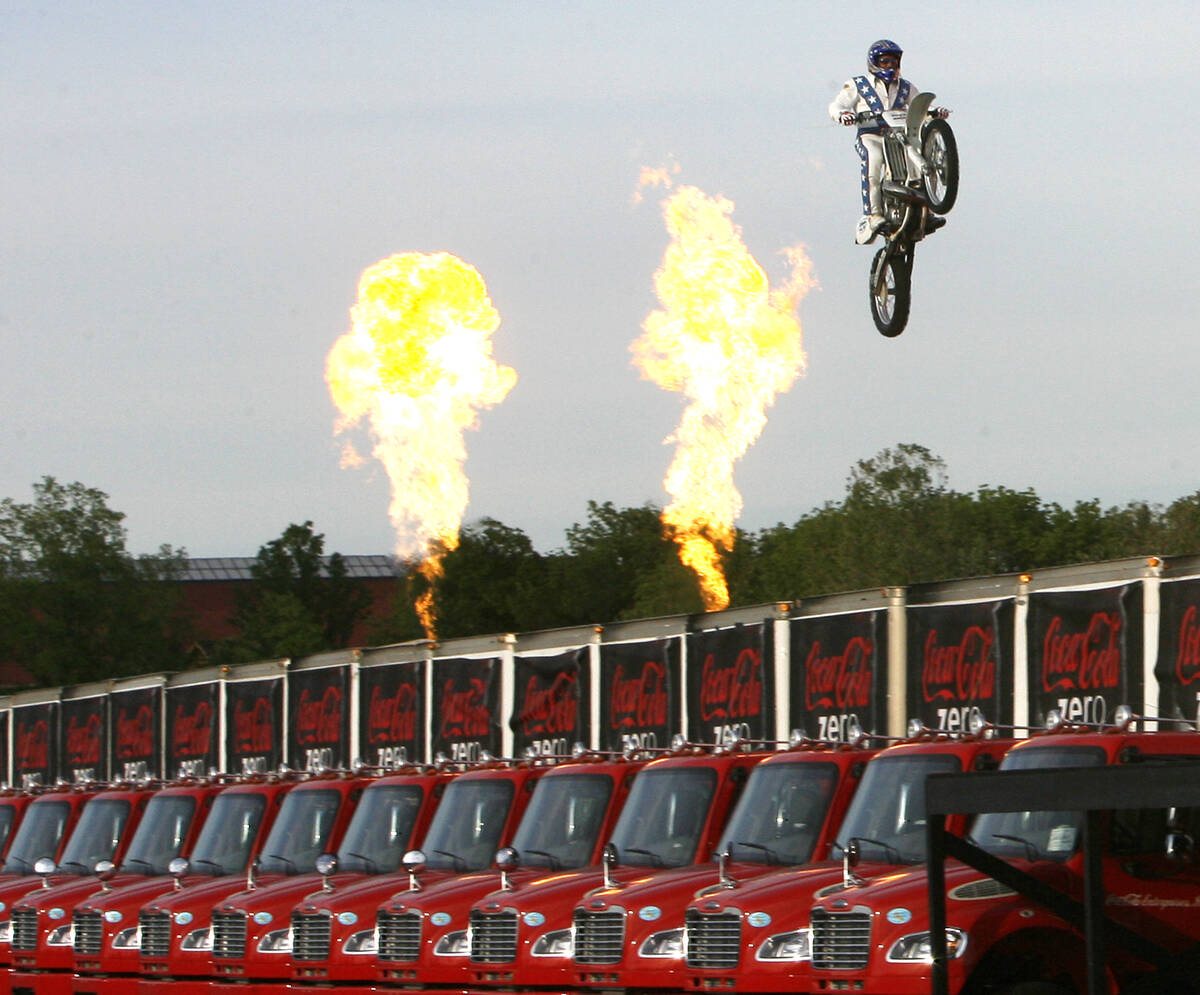 Daredevil Robbie "Kaptain" Knievel jumps over 24 delivery trucks, his longest gap ever of 200 f ...
