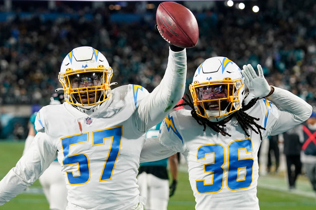 Los Angeles Chargers linebacker Amen Ogbongbemiga (57) and cornerback Ja'Sir Taylor (36) celebr ...