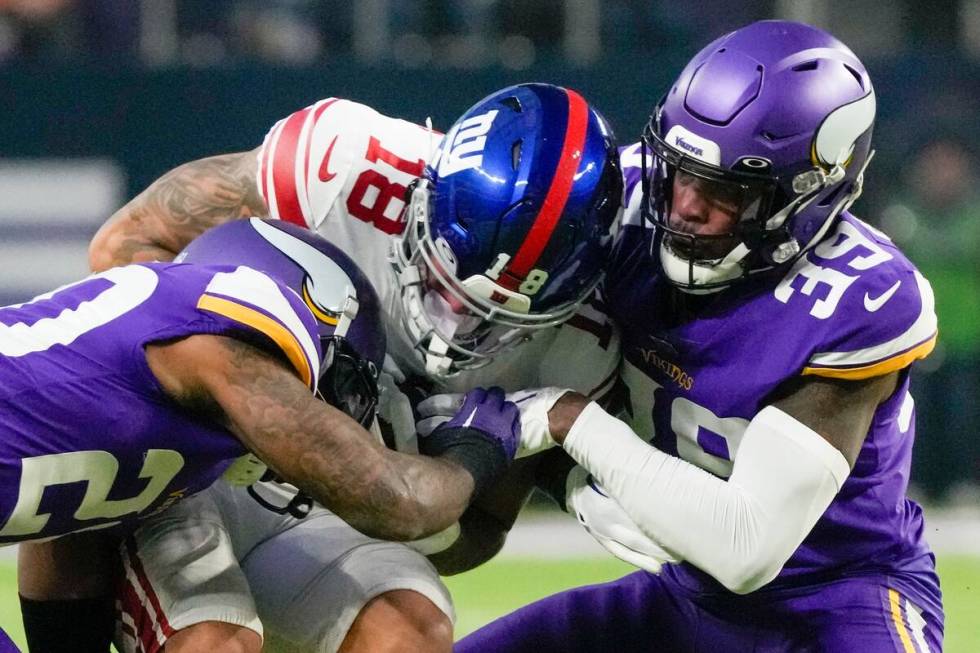 New York Giants' Isaiah Hodgins catches a pass between Minnesota Vikings' Chandon Sullivan and ...