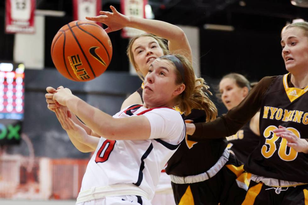 UNLV Lady Rebels guard Ashley Scoggin (0) fights for the ball against Wyoming Cowgirls guard Em ...