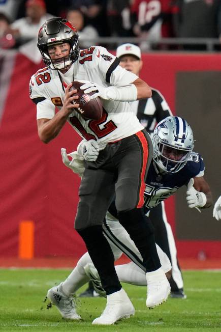 Tampa Bay Buccaneers quarterback Tom Brady (12) gets past Dallas Cowboys defensive end Dante Fo ...