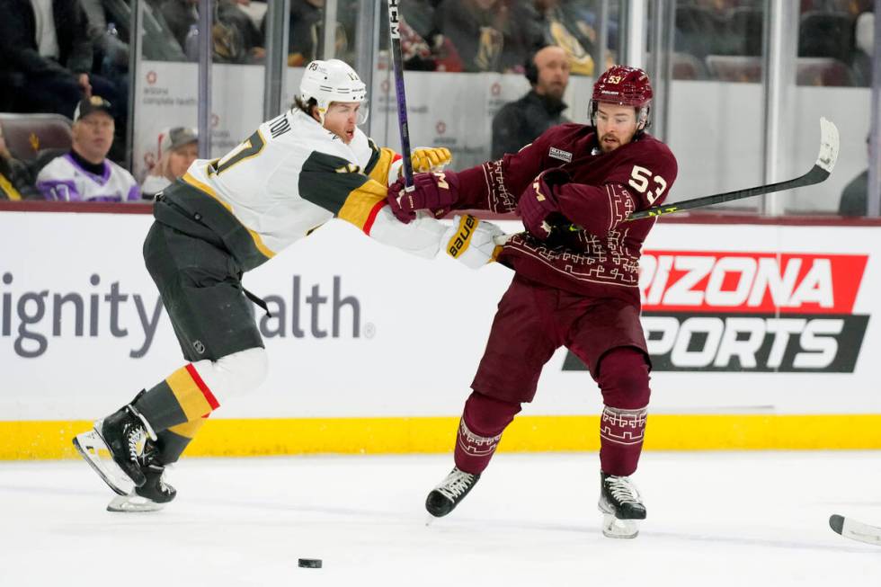 Vegas Golden Knights defenseman Ben Hutton, left, knocks Arizona Coyotes left wing Michael Carc ...