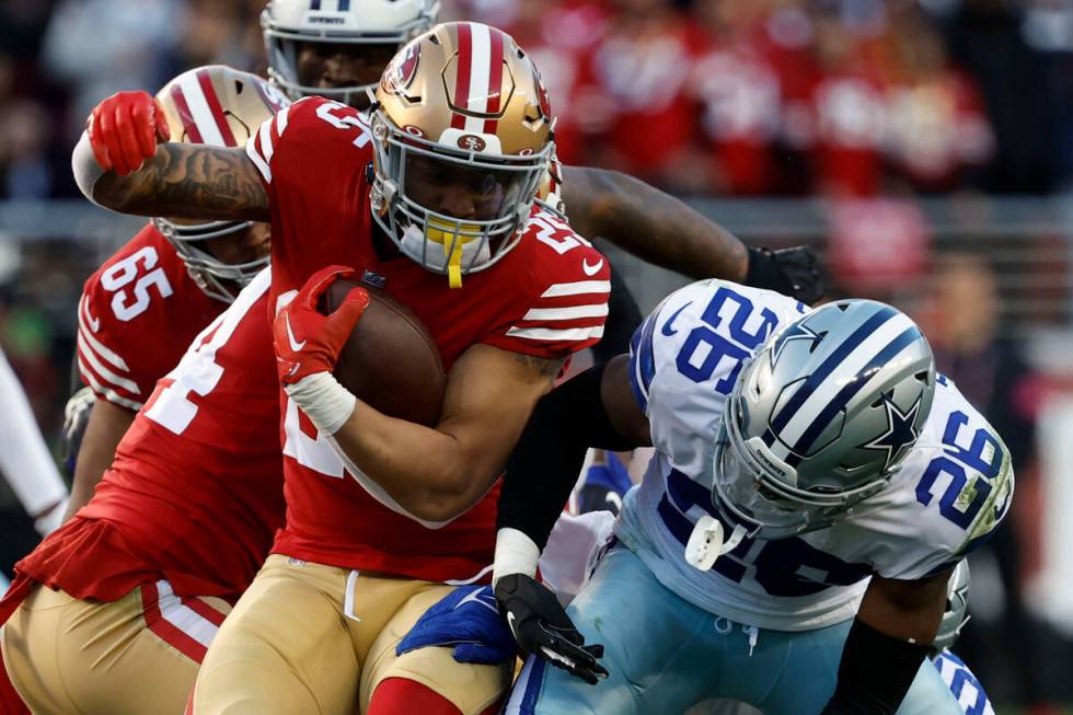 San Francisco 49ers running back Elijah Mitchell, left, runs against Dallas Cowboys cornerback ...