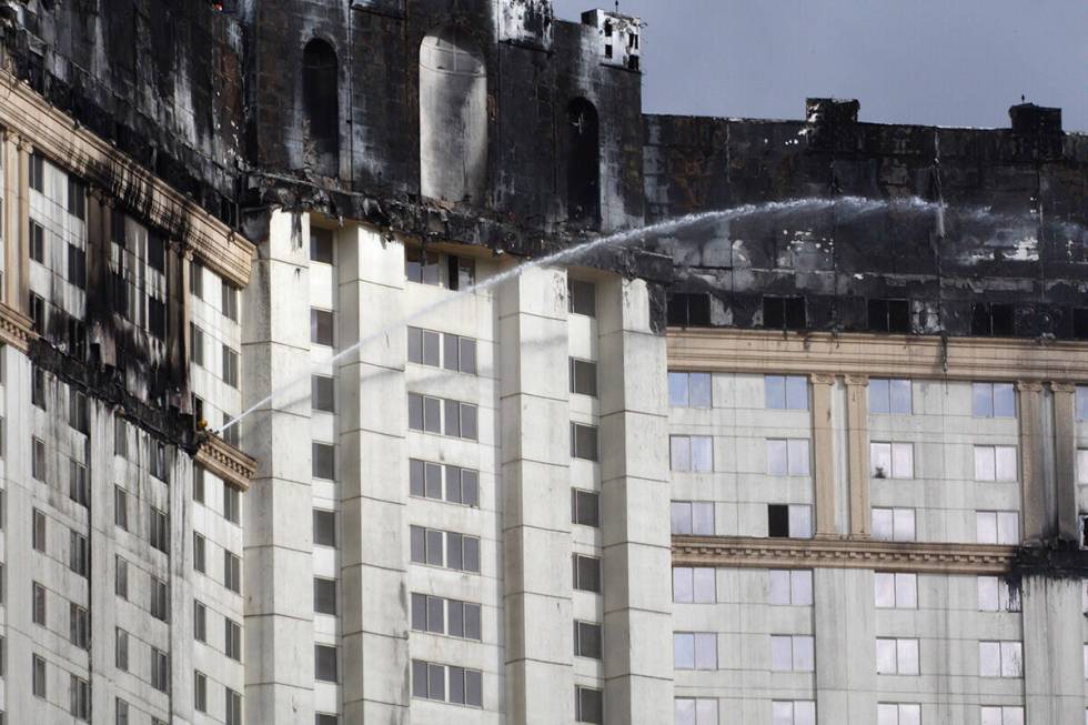 Firefighters douse hotspots on the upper level floors of the Monte Carlo hotel-casino on Friday ...