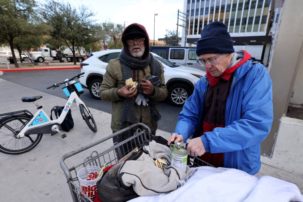 Richard Birmingham, right, offers food to Monir Rafiq during his daily bicycle outreach ride in ...