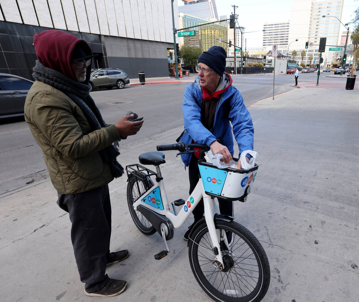 Richard Birmingham, right, offers food to Monir Rafiq during his daily bicycle outreach ride in ...