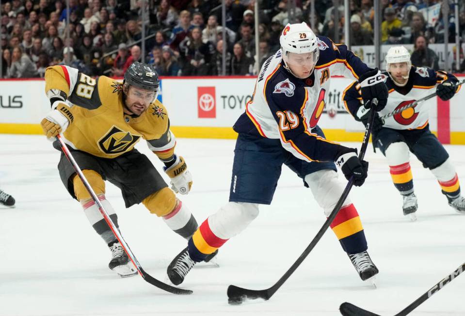 Colorado Avalanche center Nathan MacKinnon, right, shoots the puck after driving past Vegas Gol ...