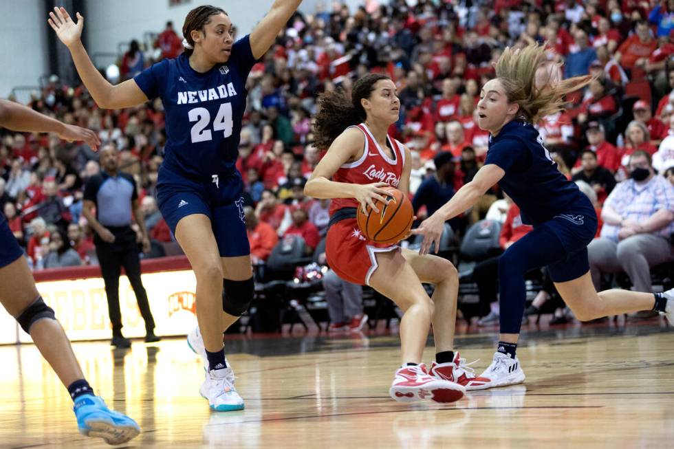 UNLV Lady Rebels guard Kiara Jackson, center, drives between Nevada Wolf Pack forward Kennedy L ...