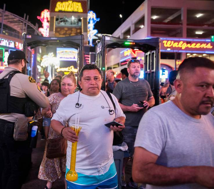 Security officers screen people as they walk through a metal detector before entering the Fremo ...