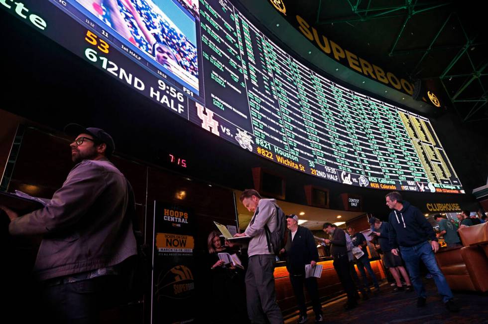 Sports bettors line up as the menu of Super Bowl props is on display at the Westgate SuperBook, ...