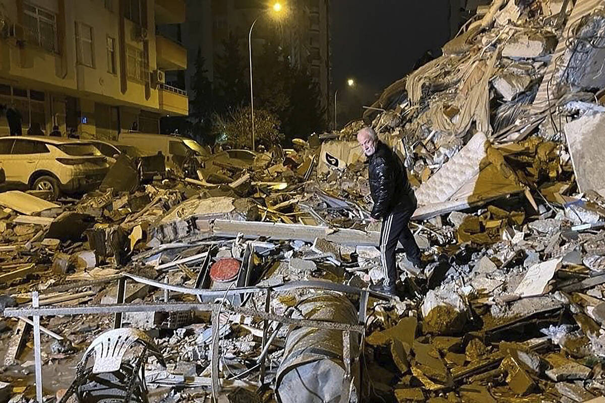 A man searches collapsed buildings in Diyarbakir, southern Turkey, early Monday, Feb. 6, 2023. ...
