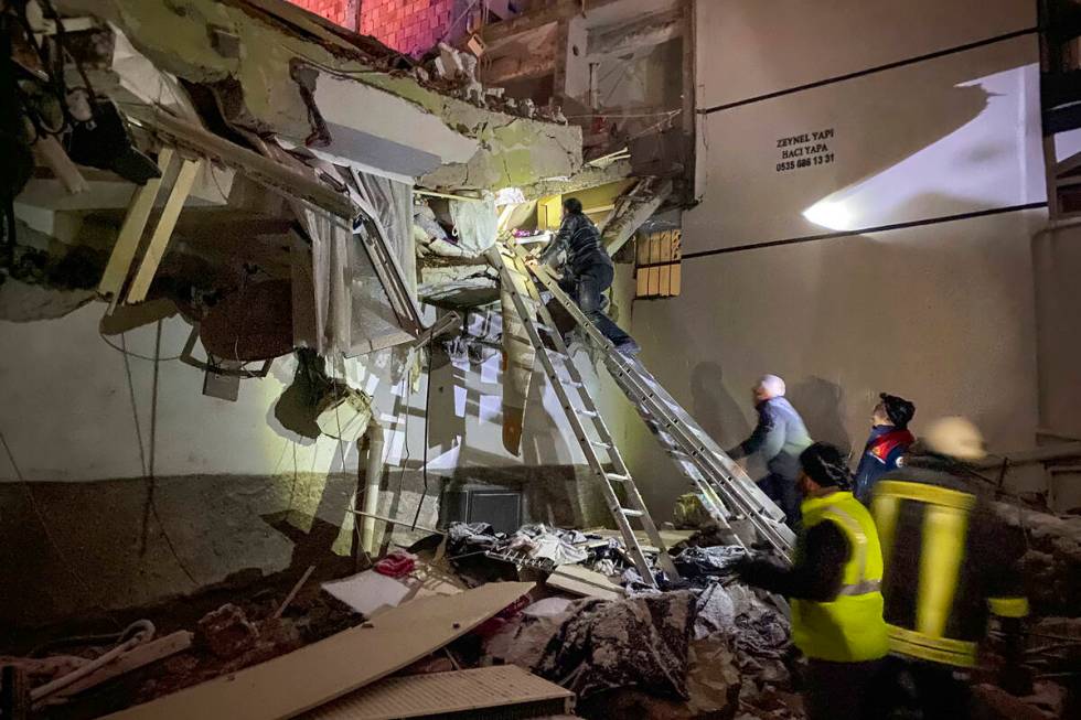 Rescue teams try to reach trapped residents inside collapsed buildings in Adana, Turkey, Monday ...