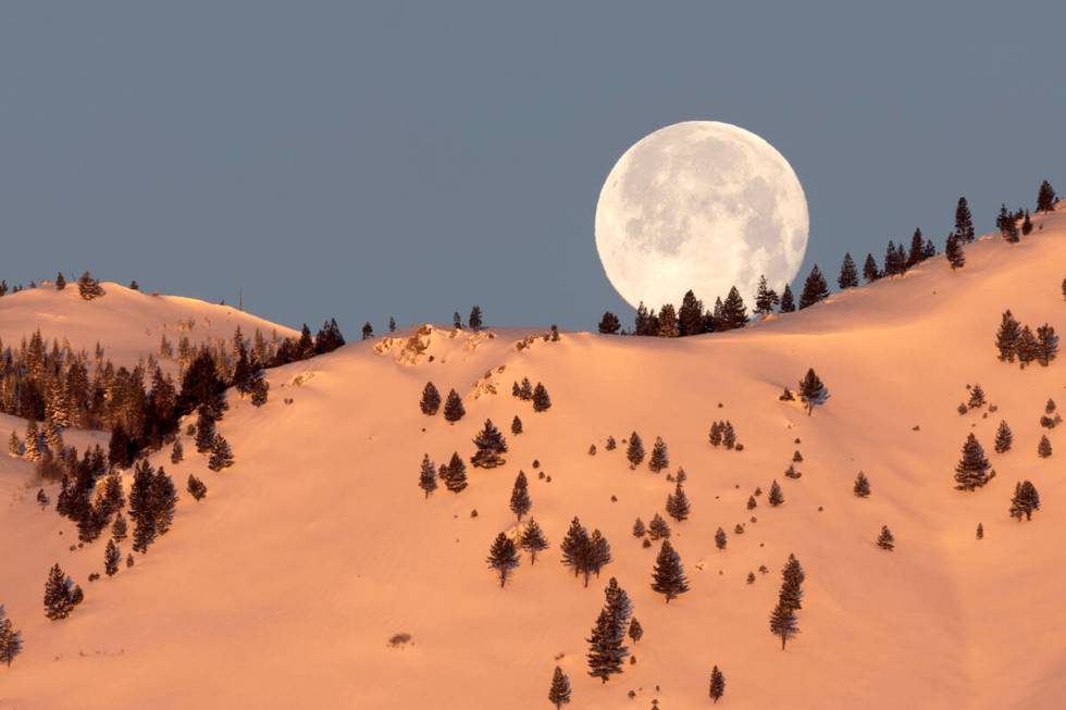 February’s Snow Moon sets behind the snow-covered mountains on Monday, Feb. 6, 2023, in Carso ...