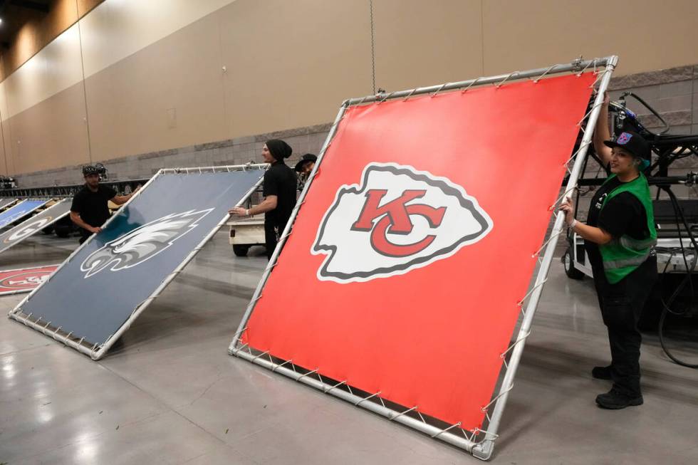 Workers hold up the logos of the Philadelphia Eagles, left, and the Kansas Chiefs as they build ...