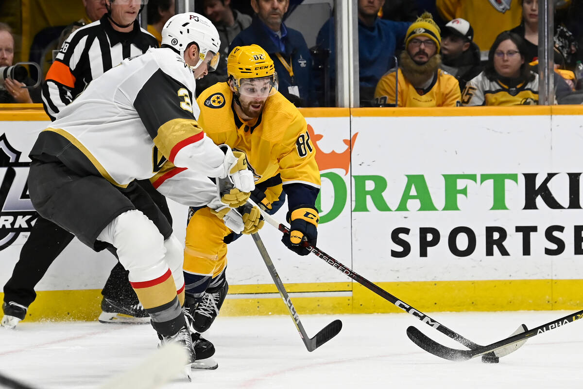 Nashville Predators center Tommy Novak (82) reaches for the puck as Vegas Golden Knights defens ...