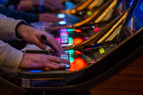 A visitor plays a slot machine with others nearby at Red Rock Casino on Tuesday, Dec. 26, 2021, ...