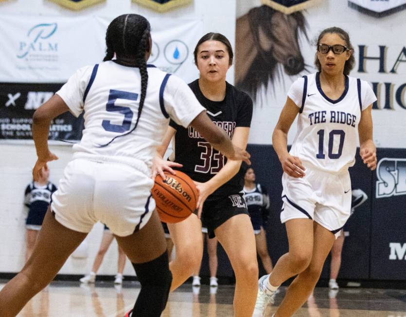 Faith Lutheran's Emma Herpin (33) drives between Shadow Ridge's Zh'mya Martin (5) and and Jasly ...