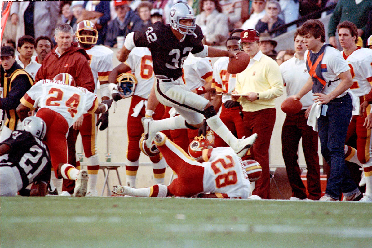 Los Angeles Raiders running back #32 Marcus Allen high steps his way down the sideline past Was ...