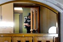 A police officer, with his gun drawn, is seen through the window at an entrance at the Michigan ...