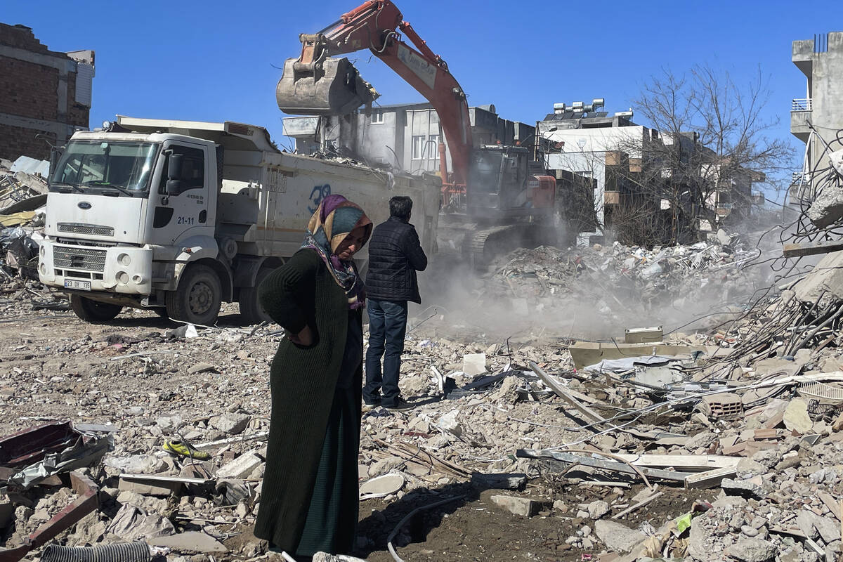 Parents of Taha Erdem, mother Zeliha Erdem, left, and father Ali Erdem stand next to the debris ...