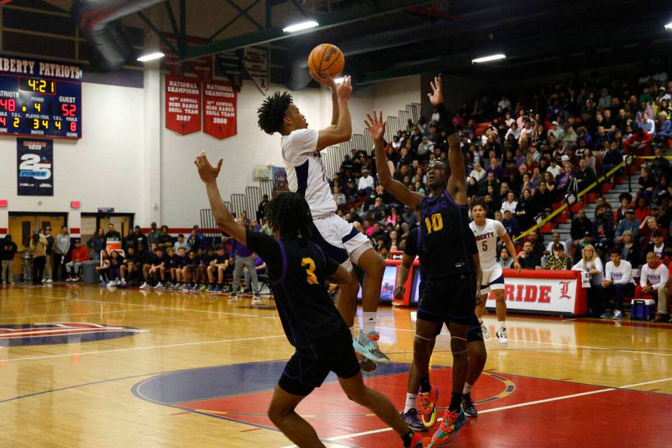 Liberty's Dedan Thomas (11) attempts a jump shot as Durango's Jevon Yapi (3) and Durango's Tyle ...