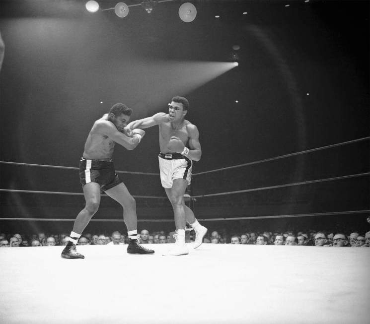 Heavyweight champion Muhammad Ali ( Cassius Clay) moves in with a series of amsshes to the f ...