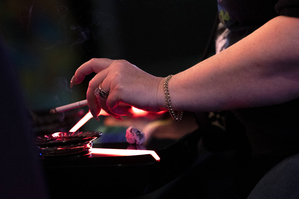 A guest at The Plaza smokes a cigarette while gambling on Thursday, March 2, 2023, in Las Vegas ...