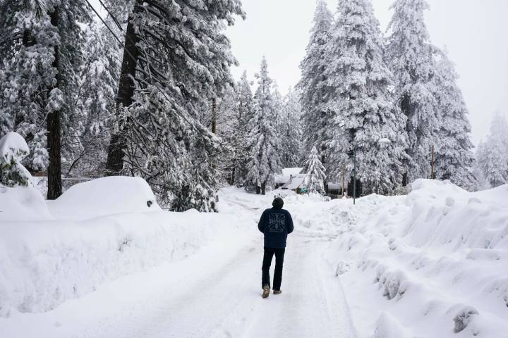 A local resident who declined to give his name walks to his home in Running Springs, Calif., Tu ...