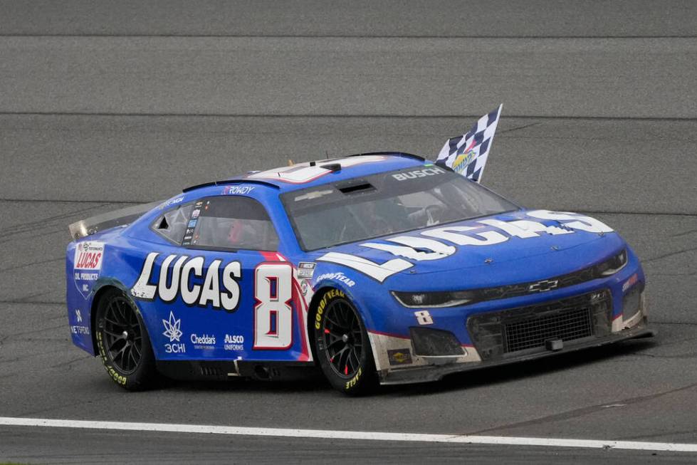 Kyle Busch waves a checkered flag while celebrating after winning the NASCAR Cup Series auto ra ...